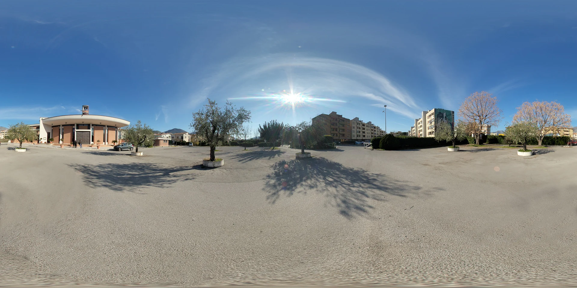 Church, Buildings and Street Art 01 HDRI preview: a sunny paved square with a low church, trees and surrounding buildings shows long branching shadows.